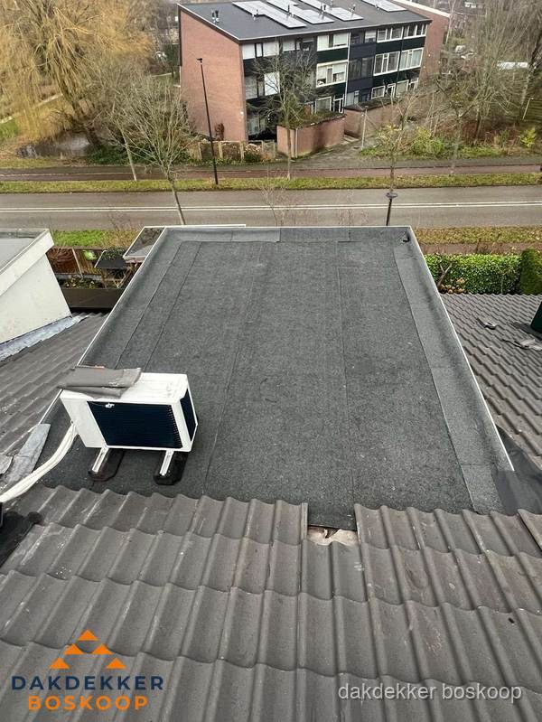 Plat dak inspectie met bitumen bedekking naast schuin pannendak in Boskoop