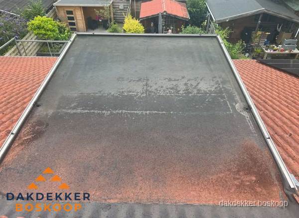 Verouderd plat dak met slijtage tussen schuine daken in Boskoop Verouderd plat dak met slijtage tussen schuine daken in Boskoop