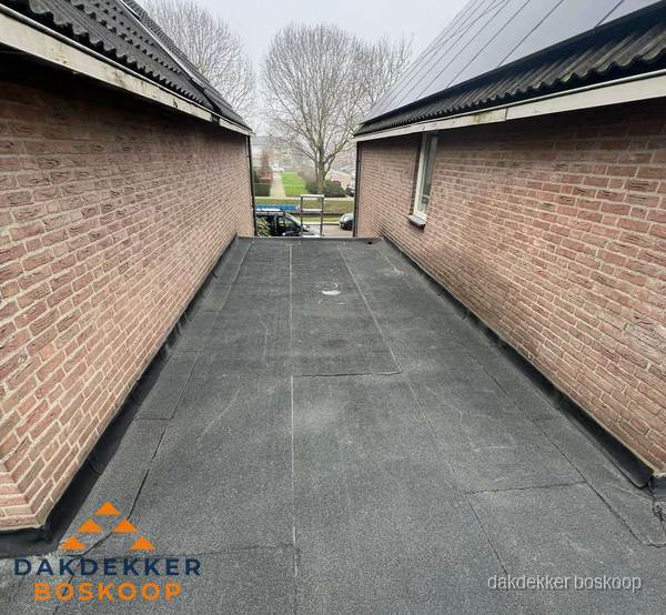Plat dak met bitumen dakbedekking tussen bakstenen muren in Boskoop Plat dak met bitumen dakbedekking tussen bakstenen muren in Boskoop